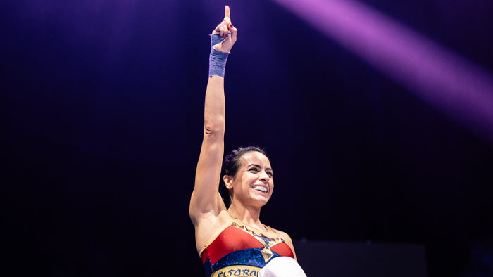 Christine Vicens celebrating arms raised with lights in background