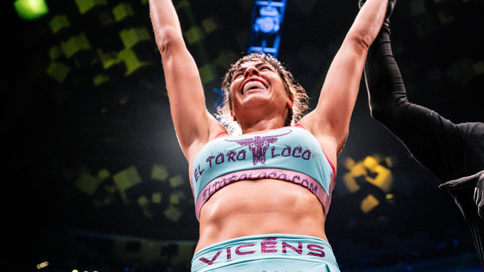 Christine Viens wearing "El Toro Loco" fight outfit, celebrating with arms raised.