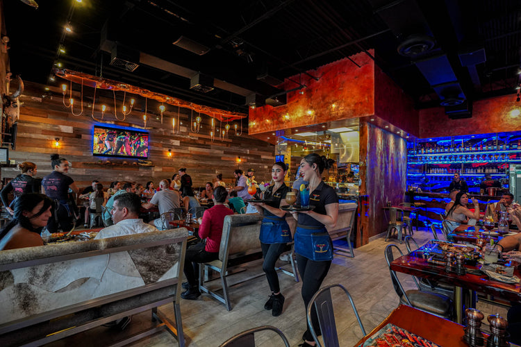 El Toro Loco Tamiami featuring bar area, guests seated at tables, and a TV screen on the wall.