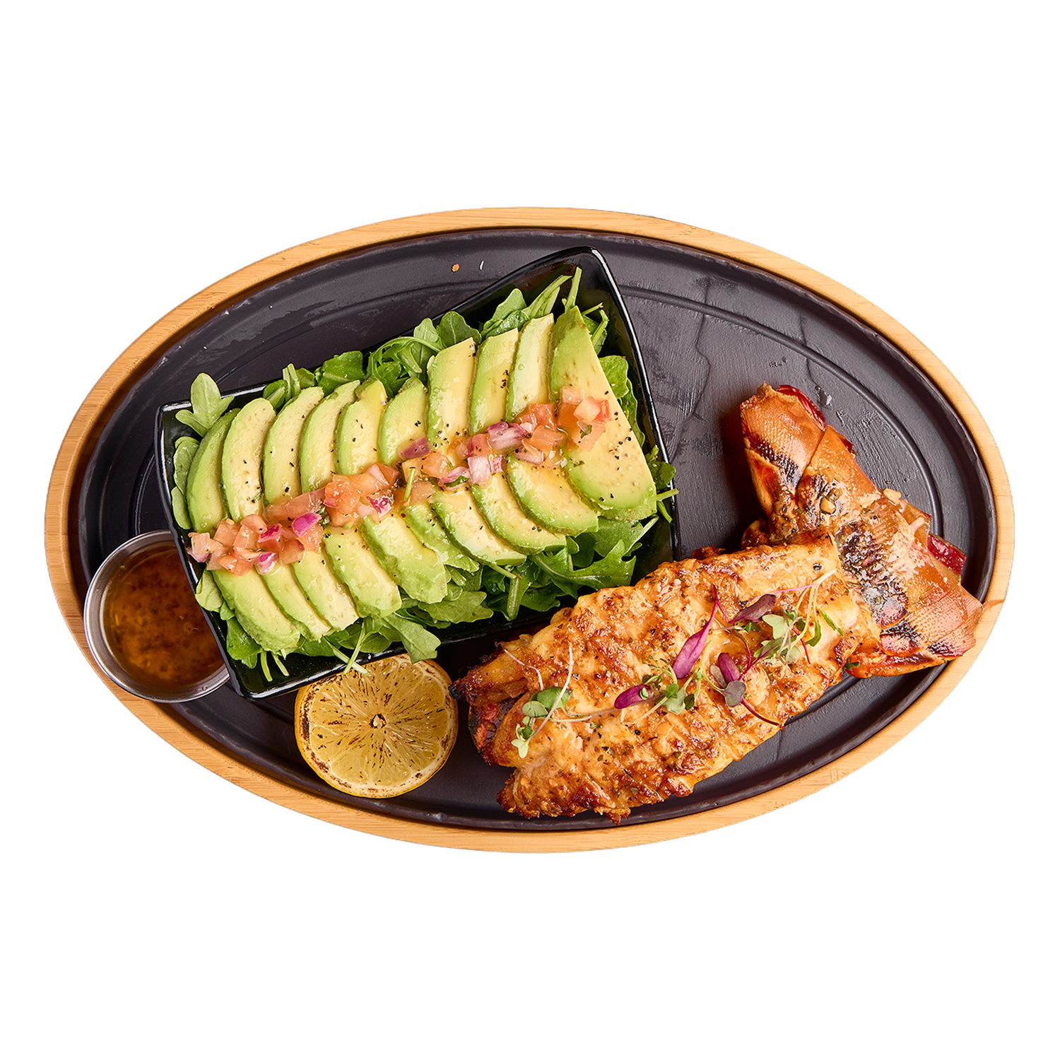 Plated dish with Lobster, avocado slices, and a side of greens on a white background.