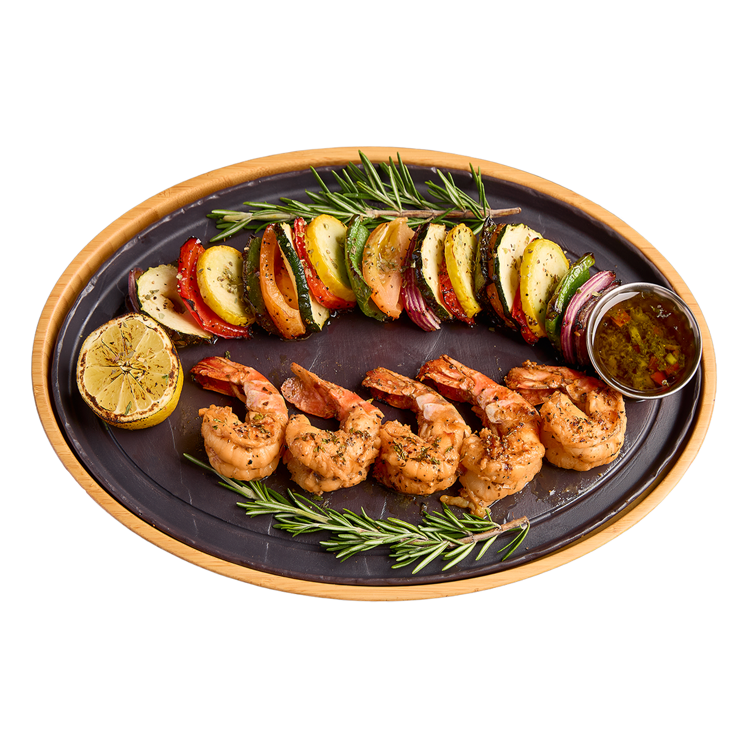 Plated dish with grilled shrimp, vegetables, and a lemon wedge on a white background
